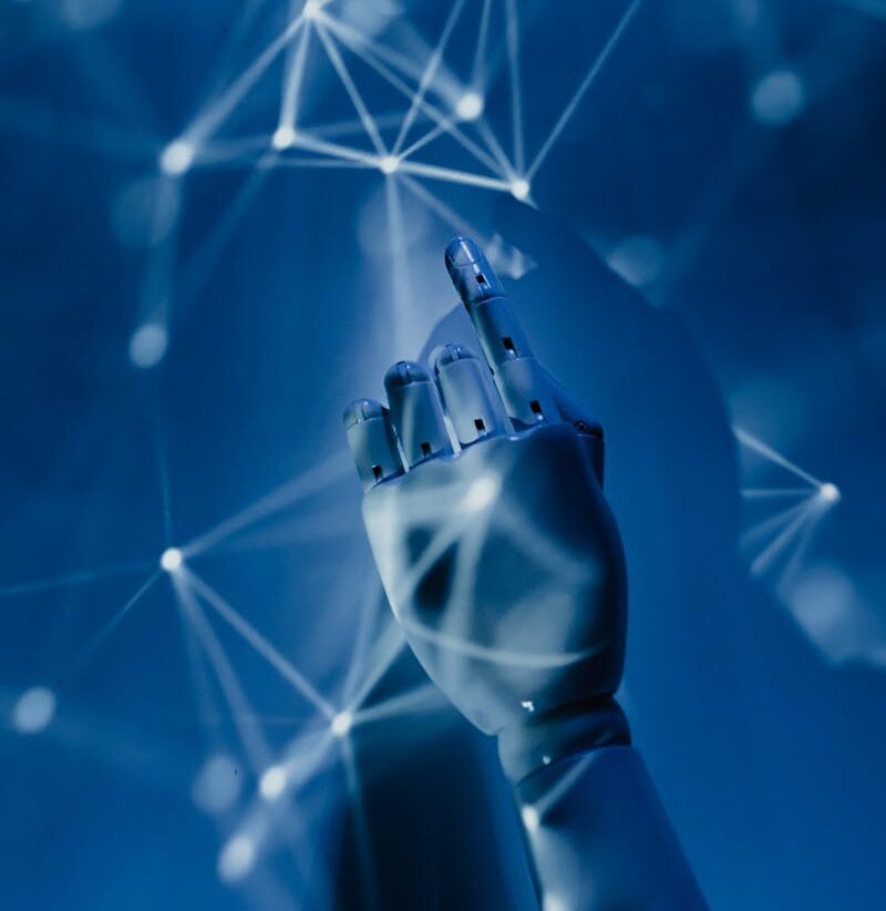 A robotic hand reaching into a digital network on a blue background, symbolizing AI technology.